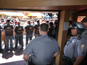 Daytona Beach Police officers keep an eye on members of the Outlaws Motorcycle Club standing shoulder to shoulder in front of Dirty Harry's bar after being ask to leave for wearing their colors inside the bar during Bike Week 2017 in Daytona Beach Saturday March 18,  2017. [News-Journal/JIM TILLER ]